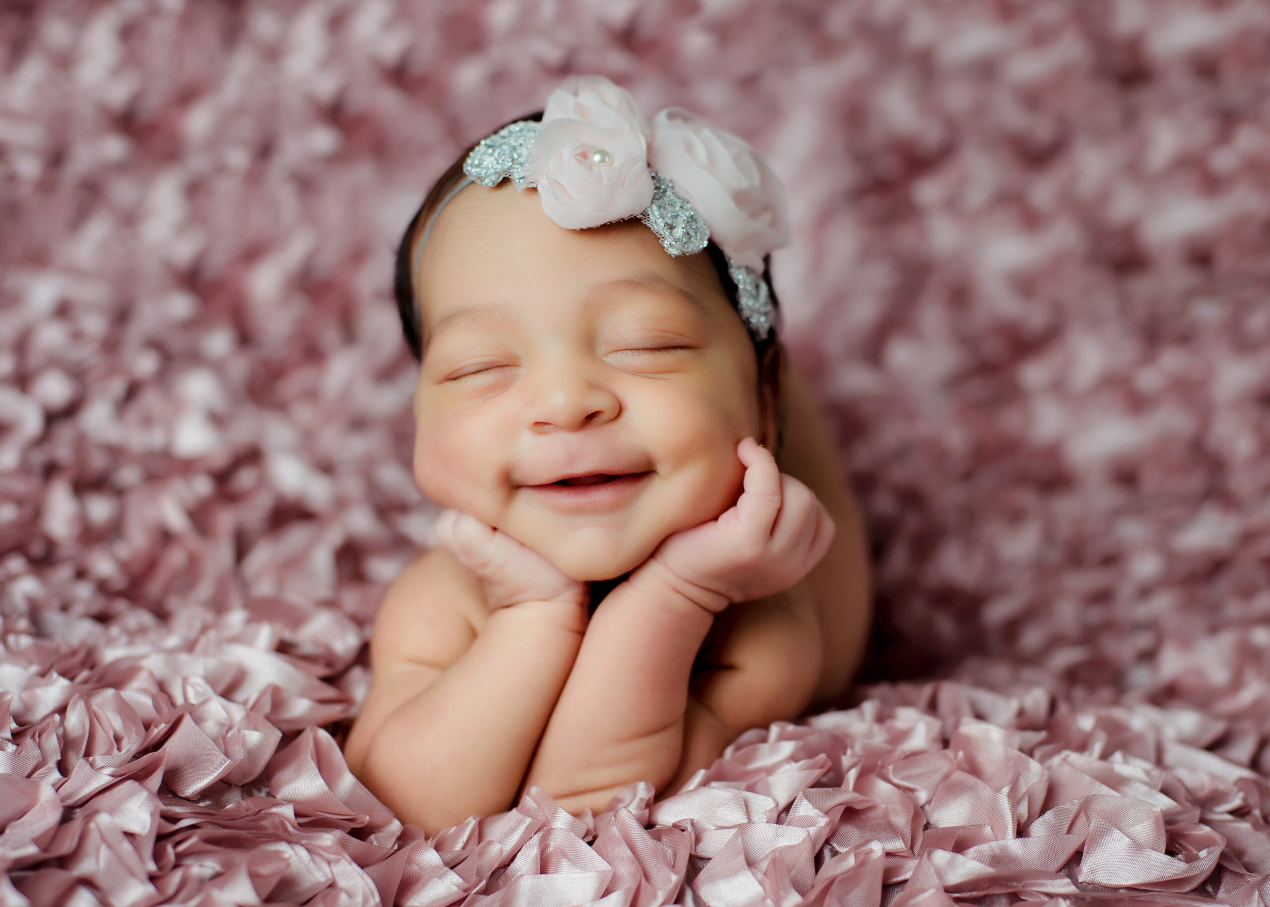 Super cute newborn baby girl smiling holding her head